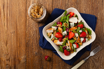 Delicious salad with fried chicken, blue cheese, strawberries and walnuts. Top view.