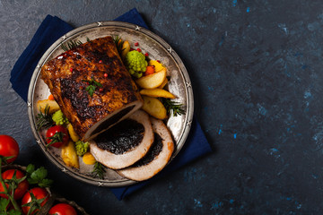 Whole roasted pork loin stuffed with dried plum. Top view. Dark blue background.