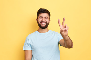 smiling cheerful young man showing two fingers up, victory sign. close up portrait, studio shot, body language, success, luck, happiness - 280886379