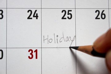 The young woman wrote the word holiday in the sequence calendar. 25, blurred photography