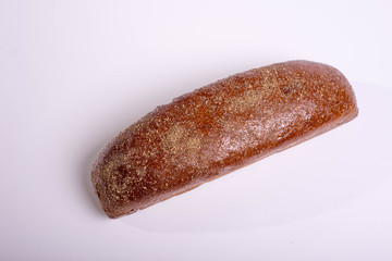 Long brown bread on a white background with crispy cumin and spices
