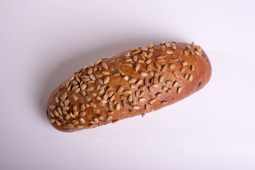 Long black bread with seeds. Baking on a white background