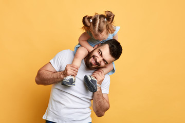 awesome positive man having fun with his little sister. isolated yellow background.entertainment.best time. unforgettable moments