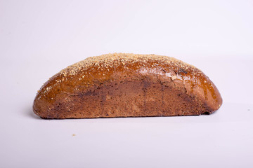 Long black bread with seeds. Baking on a white background