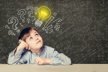 Idea! Smart kid student with lightbulb on blackboard