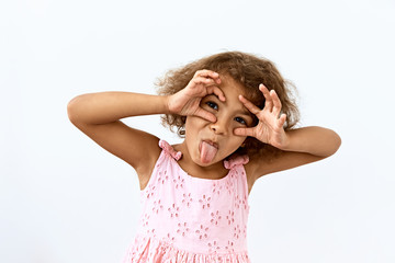 Making face,funny  foolishes portrait of little African American girl, against white background. - obrazy, fototapety, plakaty