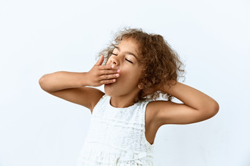 Tired,boredom and exhausted emotion. Yawning little African American girl portrait against white background