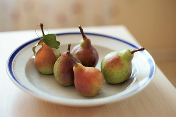 five pears in a plate on a table