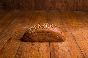 Long black bread with seeds on a wooden table. Insulated Bread Loaf