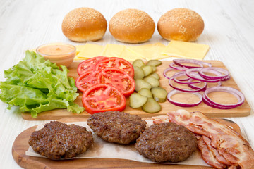 Burger ingredients on a white wooden background, side view. Close-up.