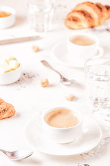 Traditional breakfast with fresh croissants on white background.