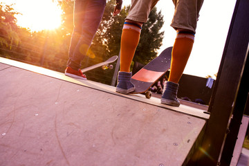Two skateboarders on the ramp in a skate park in sunset