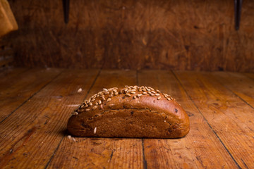 Long black bread with seeds on a wooden table. Insulated Bread Loaf