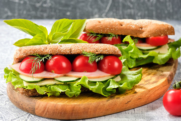 Sandwich with cheese, cucumber and Cherry Tomato on a wooden board. The sandwich is decorated with a lettuce leaf and cherry tomatoes.