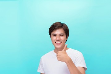 Young optimistic man isolated on blue background showing thump up with positive emotions of content and happiness. Concept of satisfaction with quality and recommendation
