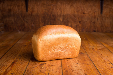 Baked bread on a brown background. Loaf of fresh bread on a wooden table