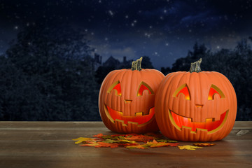 two Halloween pumpkins at night glowing