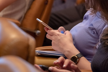 Blurred background, selective focus. Girl with a wristwatch holding a mobile phone. Retro toning.