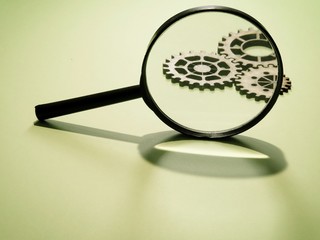 Magnifying glass with gears in the background