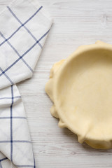 Raw dough for preparation apple pie on a white wooden background, view from above. Flat lay, top view, overhead. Close-up.