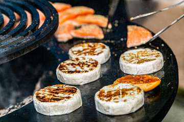 Closeup of a fresh cheese on hot grill. The chef prepares cheese on grill