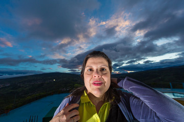 Scared Woman. Close-up shot of a woman's face with a wide angle lens an flash light from below, mixed with the clouds projecting from her head during dusk create the scary mood in the image.