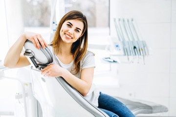 Pretty happy and smiling dental patient sitting in the dental chair at the dental office.