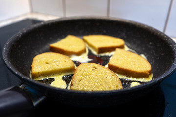 Bread croutons in an egg are fried in a pan. Close-up. Side view