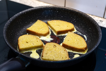 Bread croutons in an egg are fried in a pan. Close-up. Top-side view