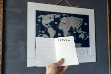 Female hands holding notebook when planning a travel route and expenses in front of the map of the world. 