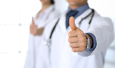 Group of doctors showing thumbs up. Perfect medical service in clinic. Happy future in medicine and healthcare concept