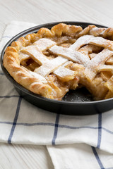 Home-baked apple pie on cloth on a white wooden background, side view. Close-up.