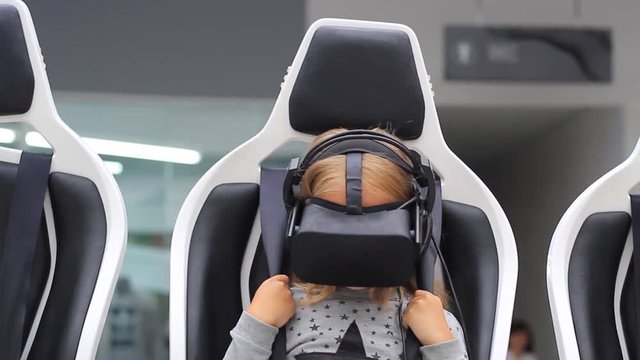 A child with a virtual reality headset. The girl sits in a chair with special effects.