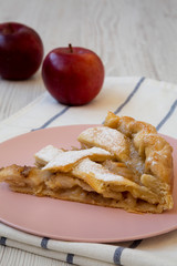 Slice of home-baked apple pie on a pink plate, low angle view. Close-up.