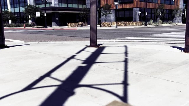 Time lapse of a spinning vertical wind tower's shadow on the sidewalk next to a busy street