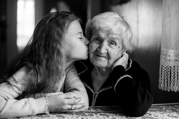 A little girl kisses her happy grandmother. Black and white photo..