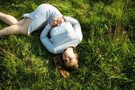 Top picture of a young girl lying in the green grass.