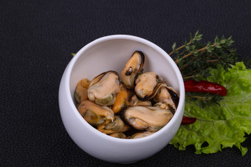 Pickled mussels in the bowl served pepper, garlic and salad