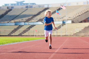 Fototapeta na wymiar Child running in stadium. Kids run. Healthy sport.