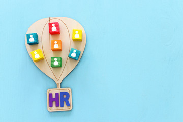 Business image of wooden air balloon with people icons over blue table, human resources and...