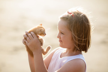 Little girl holding baby cat. Kids and pets