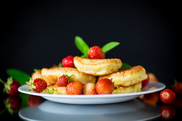 fried sweet pancakes with ripe strawberries in a plate