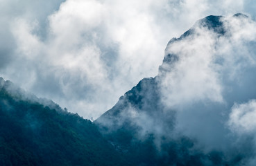 High mountains with forested slopes and peaks hidden in the clouds.