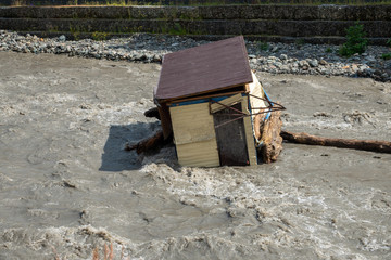 A small house destroyed the mudflow in the mountains. A small house was washed away by a flooded mountain river..