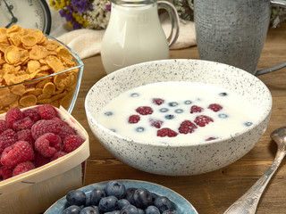 Breakfast.Corn sticks ,and cereal with milk.Raspberries and blueberries.On the background colors