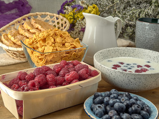 Breakfast.Corn sticks ,and cereal with milk.Raspberries and blueberries.On the background colors
