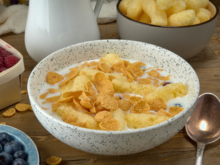Breakfast.Corn sticks ,and cereal with milk.Raspberries and blueberries.On the background colors
