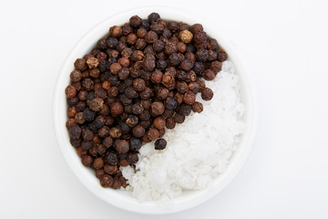 Bowl of black pepper with salt on white