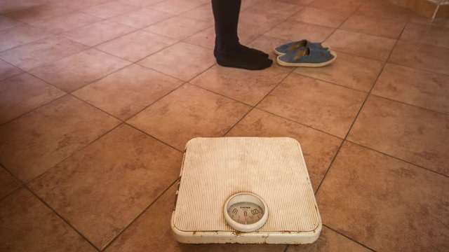 girl walking towards the scale and weighing on the scale seen in stop motion