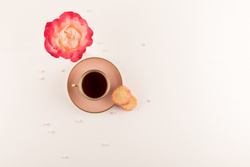 Teatime, Pink cup of tea, Pink rose and biscuits / Cookies on white table. top view. Copy space